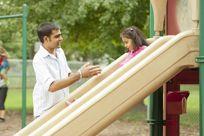 father helping daughter down a slide