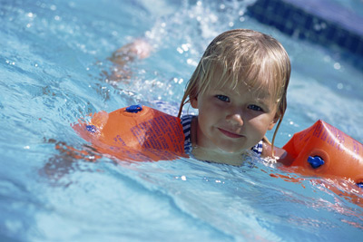 girl swimming with swimmies on her arms