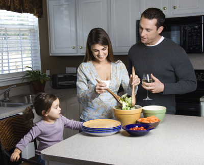 Mother, father, and young daughter making a salad